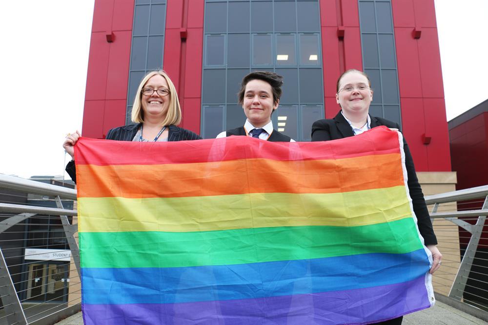 Flying the rainbow flag to celebrate the college’s high-ranking in the Top 100 Employers list are (from left), Louise Knott; Alex Belcher, chair of student LGBT network ‘Connected’; and Jane Hawksford, chair of the staff LGBT network group.