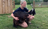 Image of a women handling a goat on a farm