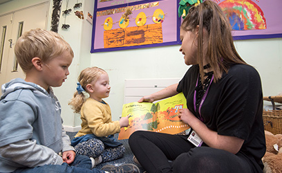 Image of a young woman reading a story to toddlers