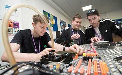Image of a group of male students working on computer circuitry.
