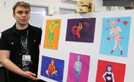 Image of a young man standing next to his artwork in an exhibition.