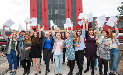 photo of students cheering whilst holding their a level results